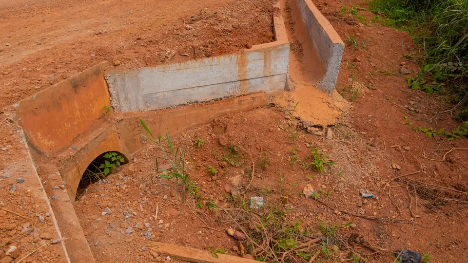 Concrete side drain and culvert opening beside an earth road