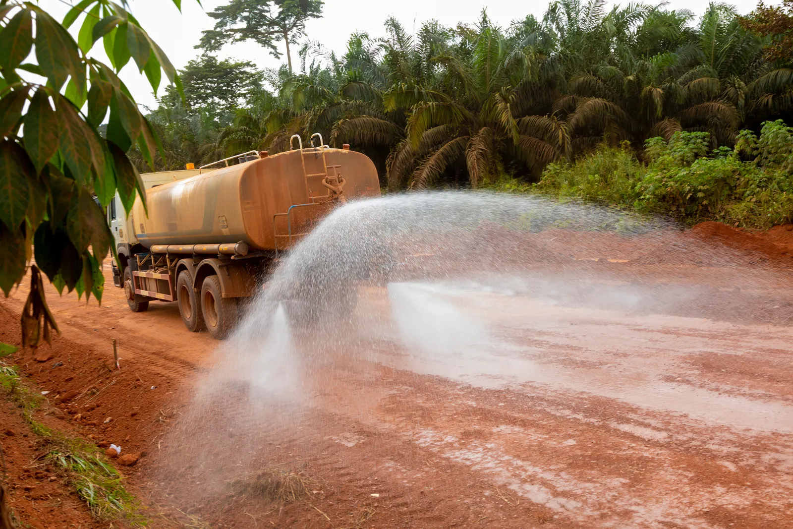 Water tanker spraying the road surface ahead of compaction