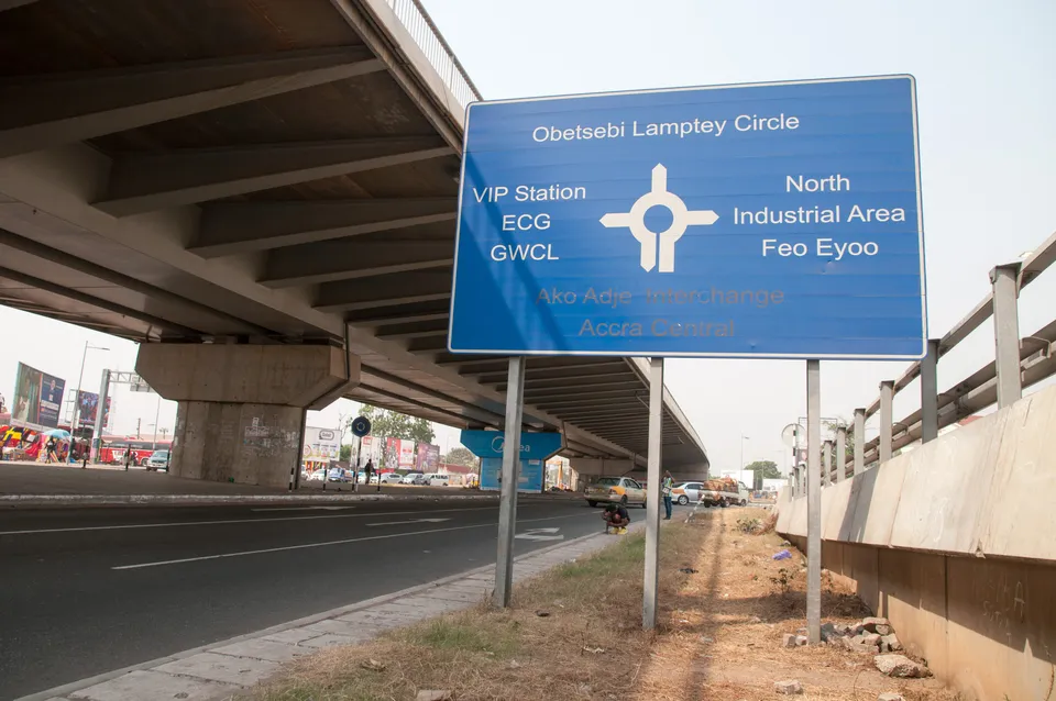 Direction sign at Obetsebi Lamptey Circle, Accra, beside a flyover