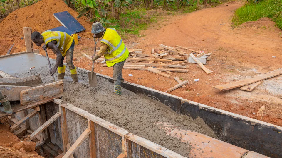 Site crew placing concrete in a roadside drain