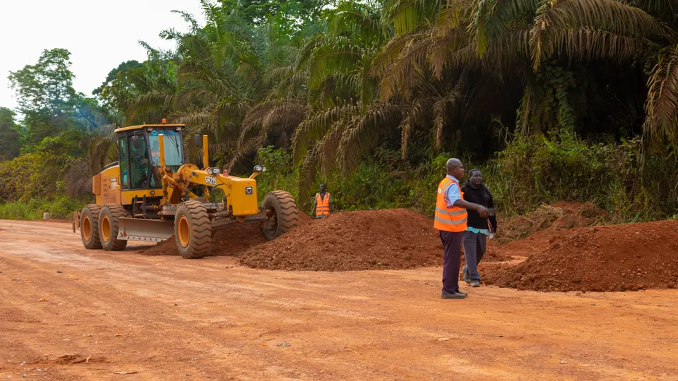 Motor grader working while site staff check the road formation