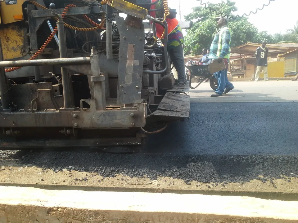 Asphalt paver laying a new bituminous surface on a road in Ghana